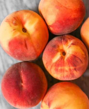 Vibrant peaches clustered together on a marble surface.