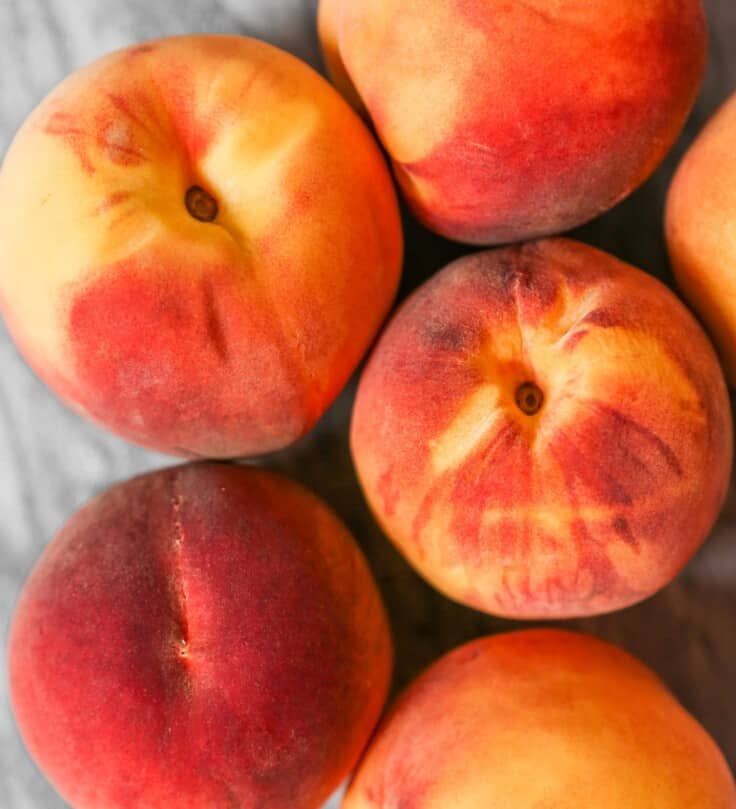 Vibrant peaches clustered together on a marble surface.