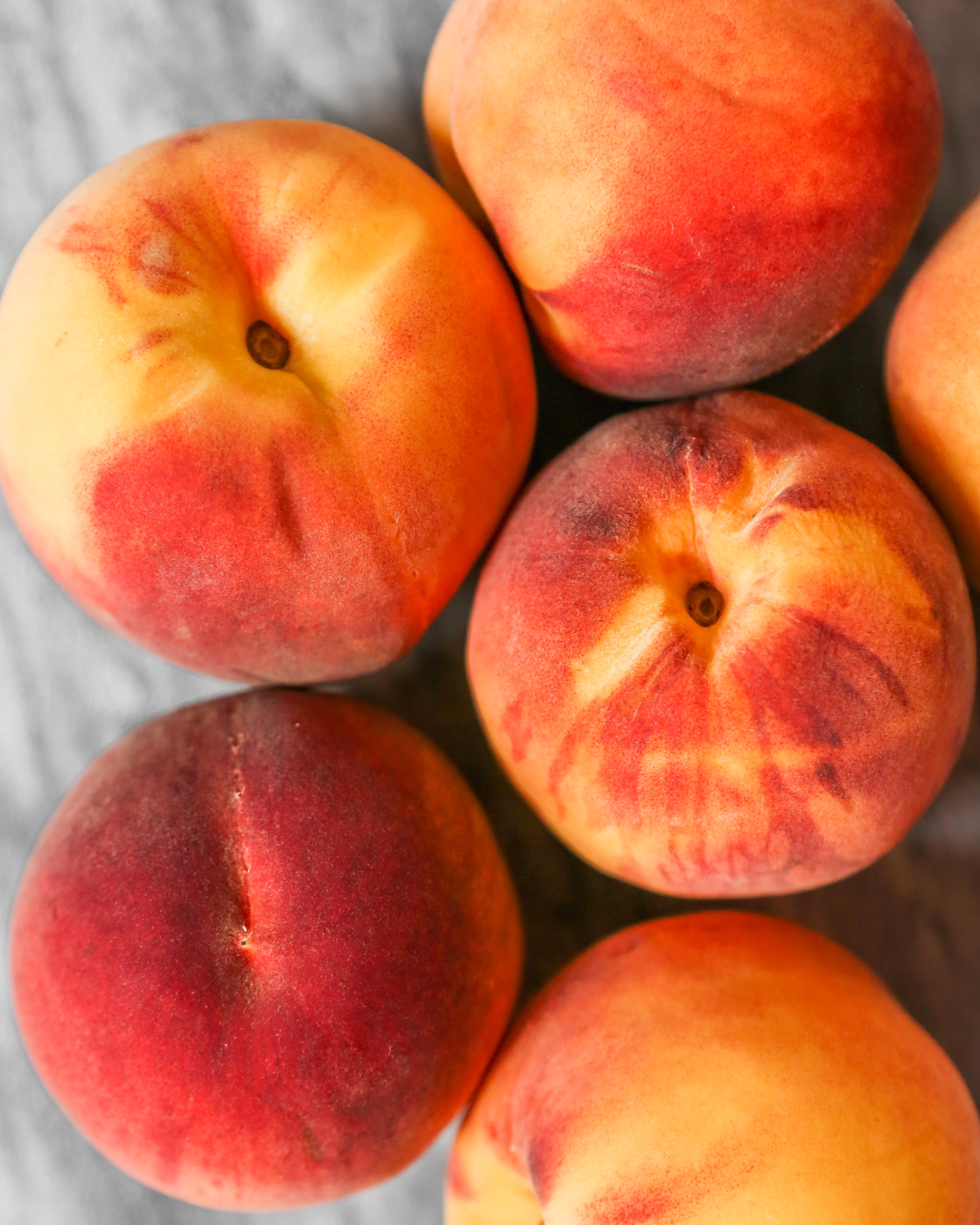 Vibrant peaches clustered together on a marble surface.