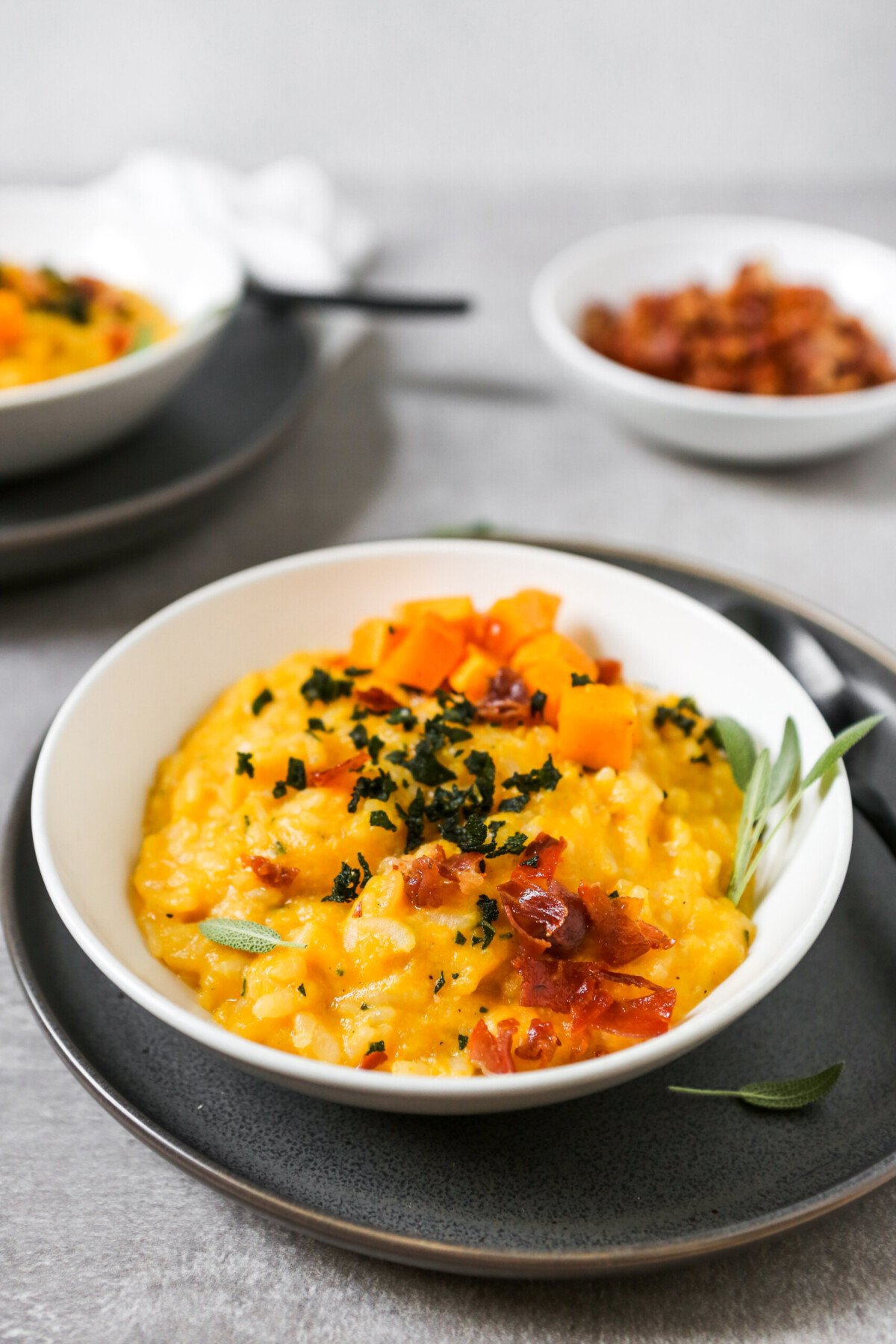 butternut squash risotto in a white bowl set on a gray plate