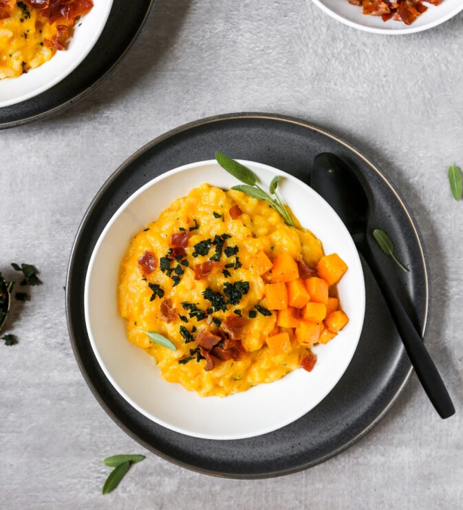butternut squash risotto in a white bowl set on a gray plate