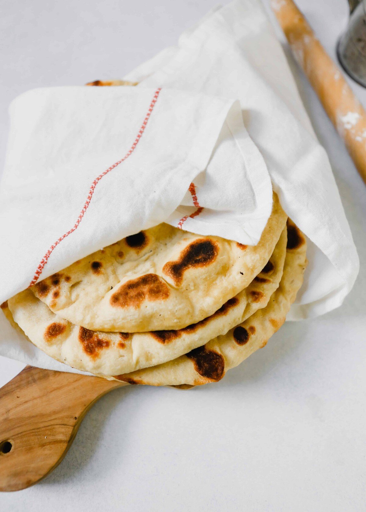 Homemade naan bread wrapped in a white towel