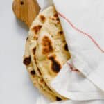 Homemade naan bread wrapped in a white towel