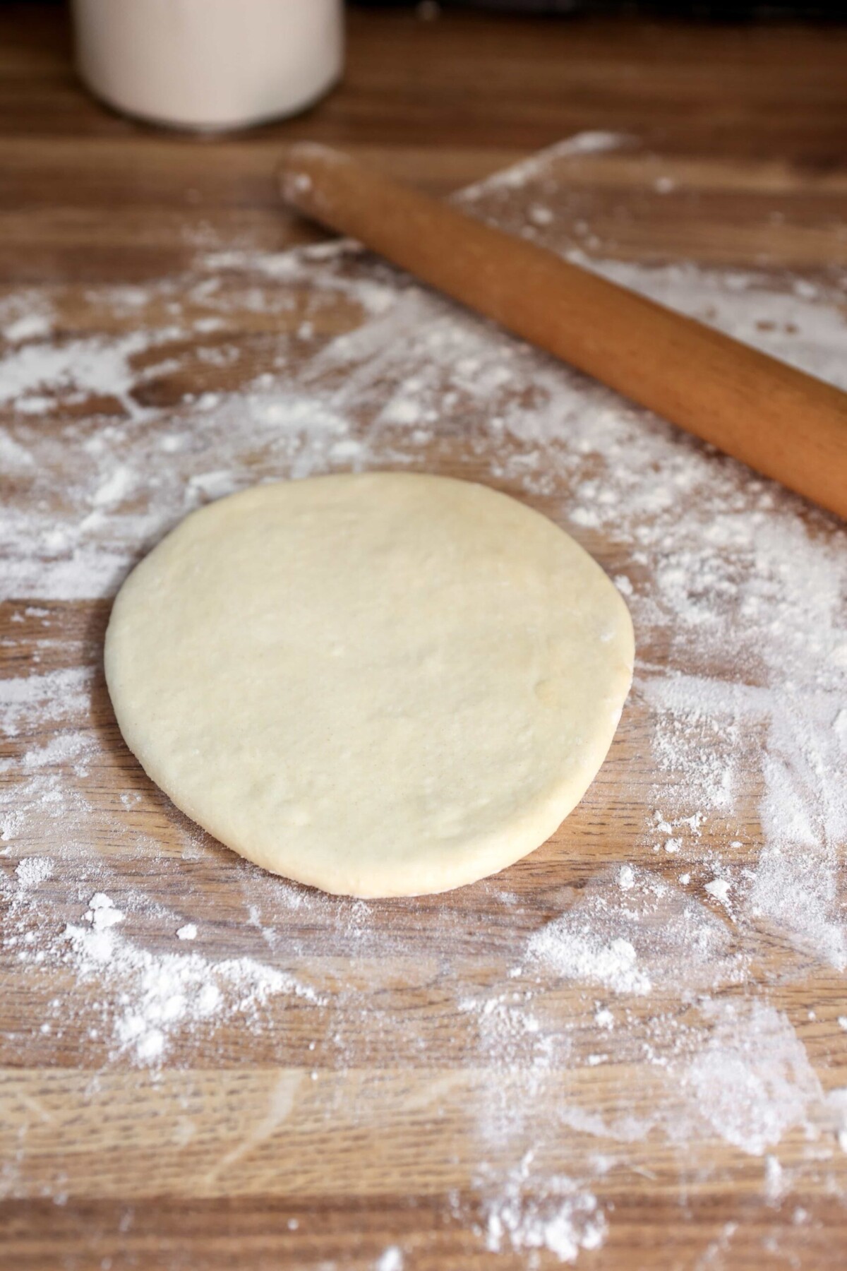 naan dough partially rolled out on floured surface