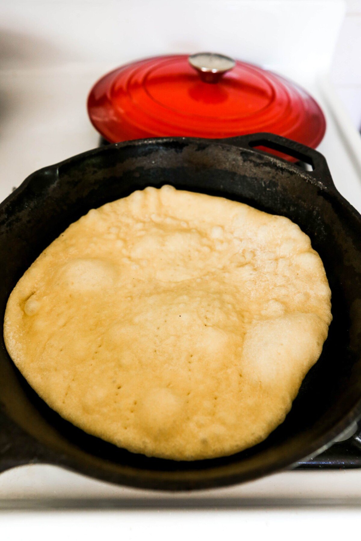 Homemade naan being cooked in a cast-iron skillet