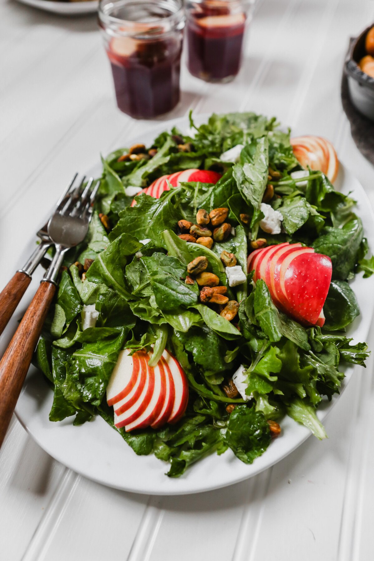 Photography of kale apple salad on a large white plate set on a white surface. 