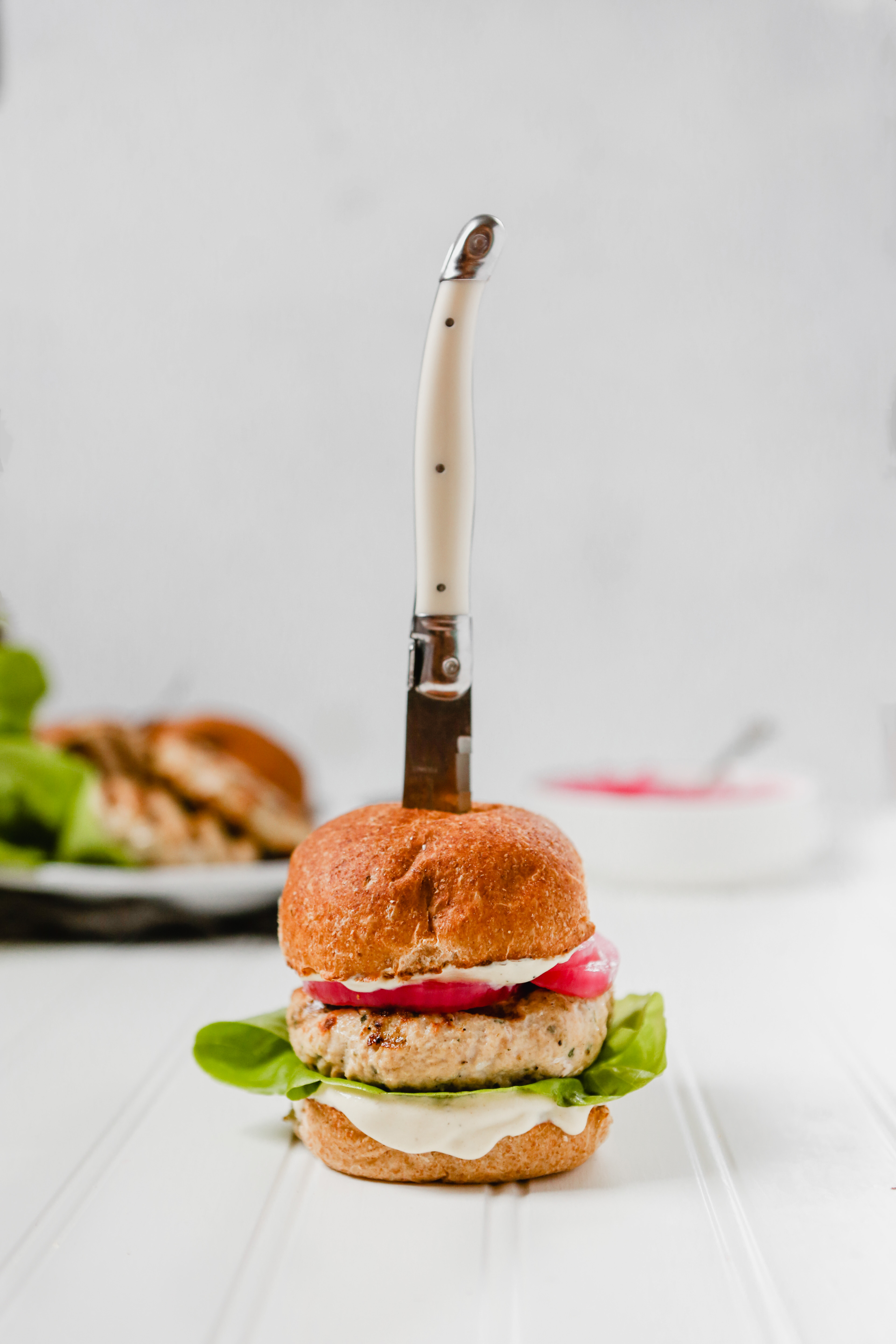 Photograph of turkey burger with steak knife stuck through the top