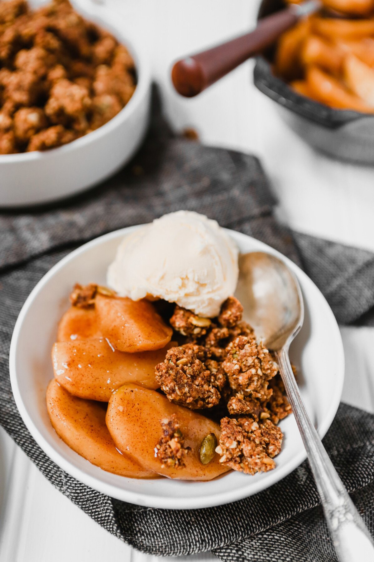 Photograph of healthy apple crisp in a white bowl set on a white background 