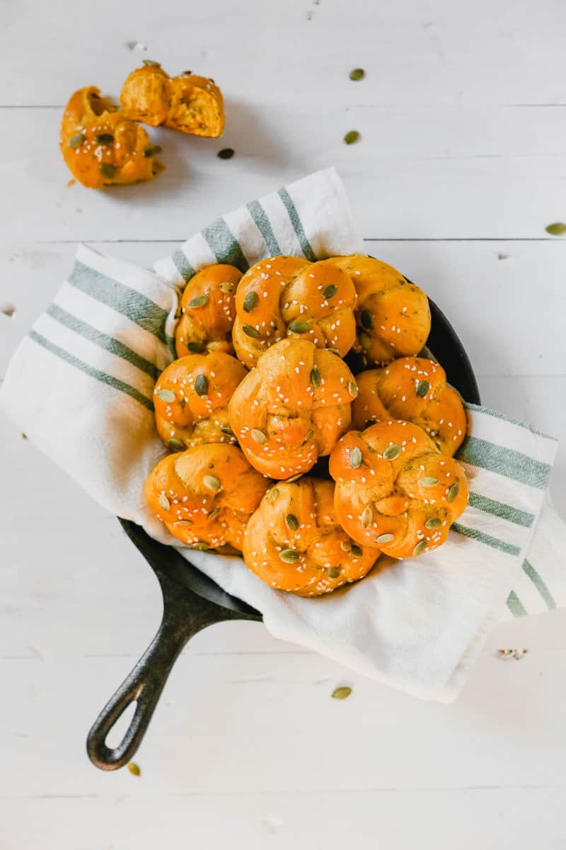 overhead photo of pumpkin challah rolls piled into a cast iron skillet