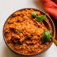 red-orange pasta sauce in a bowl with a gold spoon set in it