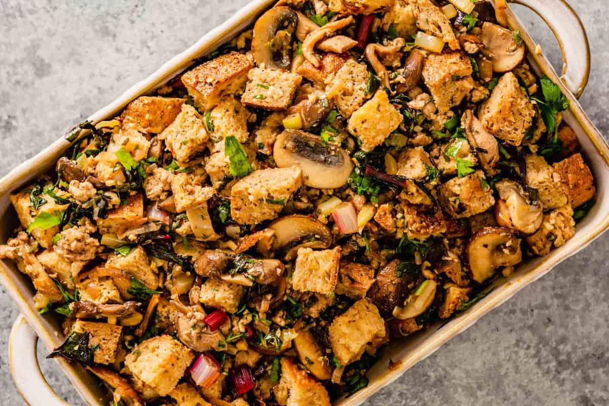 unbaked stuffing with greens and mushrooms in a 9x13-inch baking dish