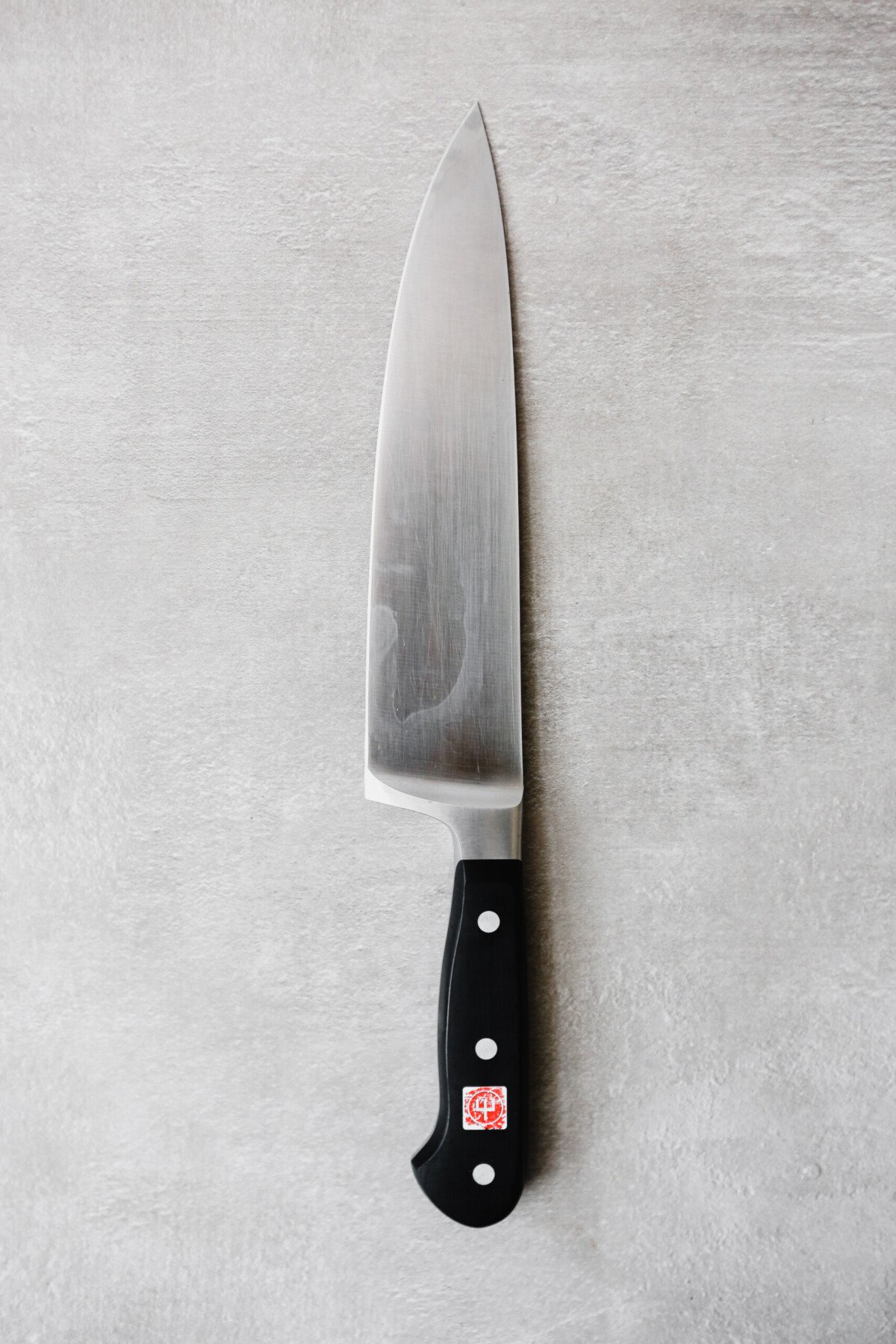 Photograph of a chefs knife on a gray table