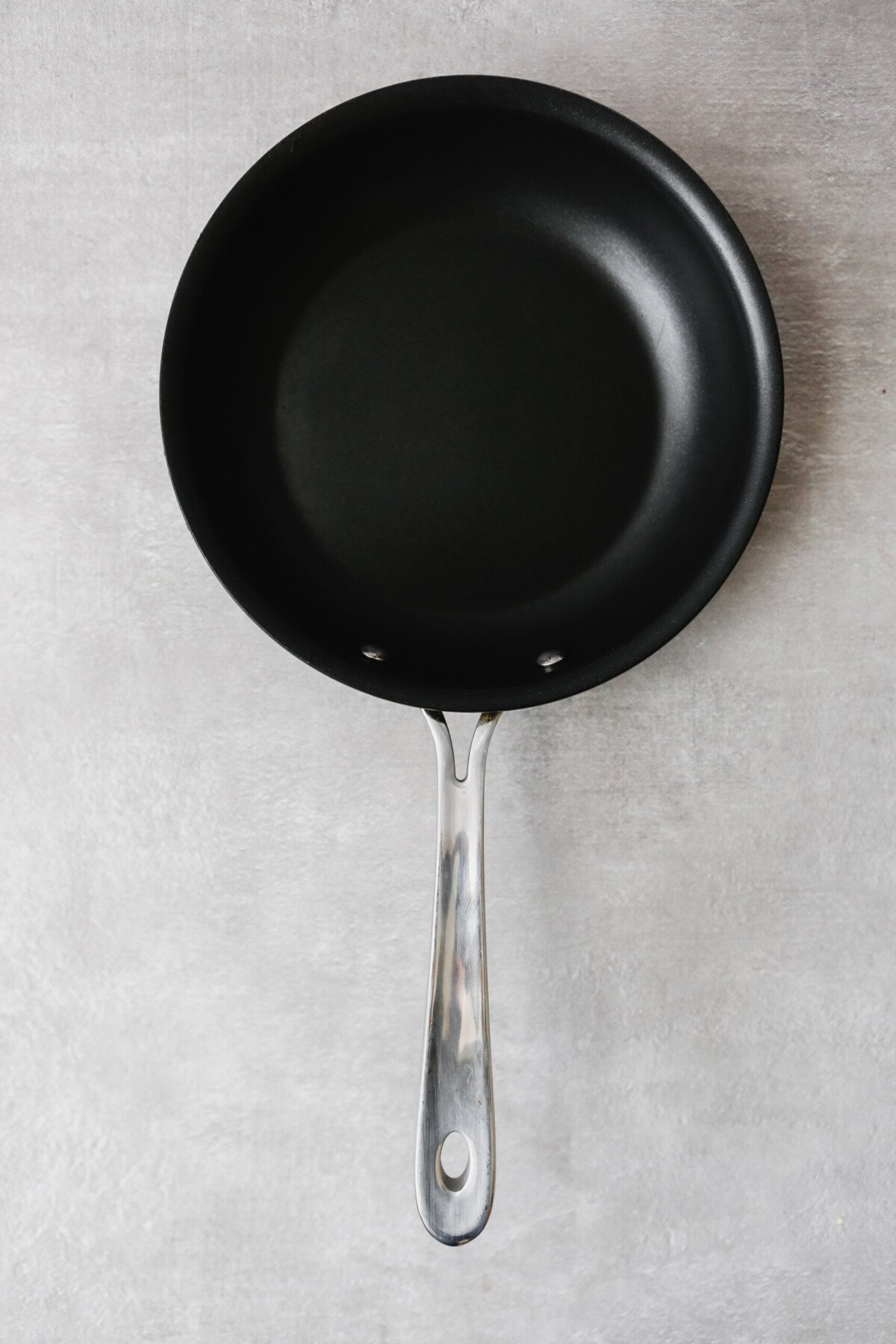 Photograph of a nonstick All-Clad skillet on a gray table
