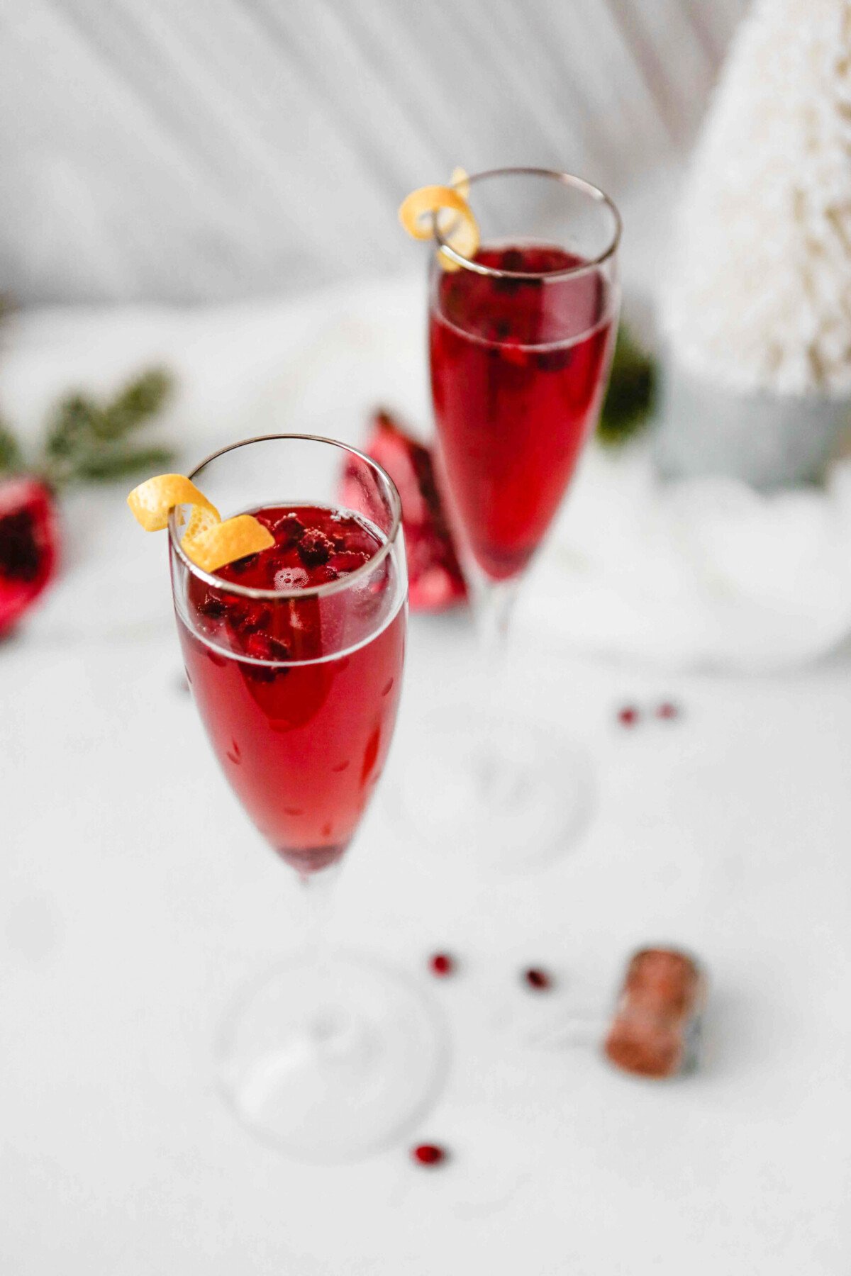Photograph of pomegranate kir royale cocktail in two flutes, cheersing