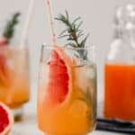 Photograph of a homemade grapefruit soda with a grapefruit slice, sprig of rosemary and white straw