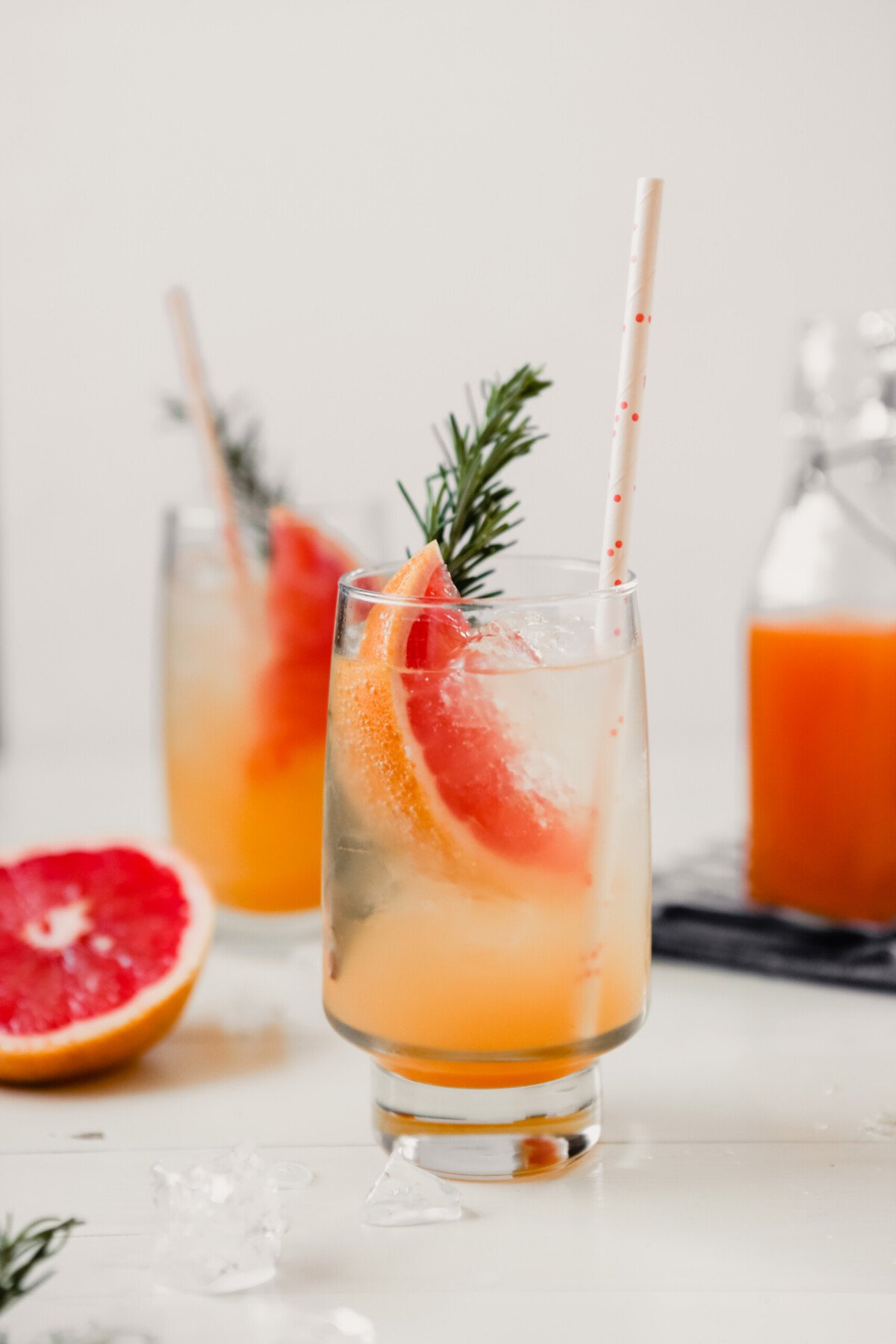 Photograph of a homemade grapefruit soda with a grapefruit slice, sprig of rosemary and white straw