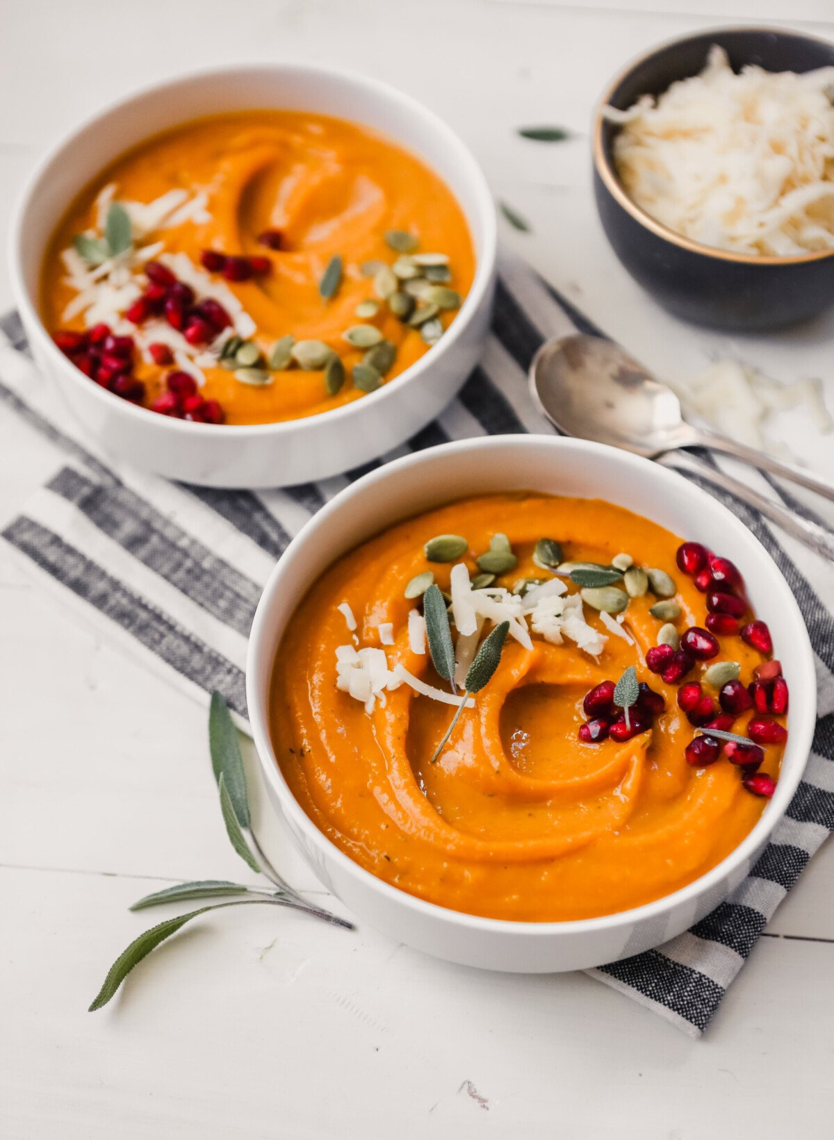 Photograph of creamy butternut squash bisque topped with pepitas and pomegranate seeds. 