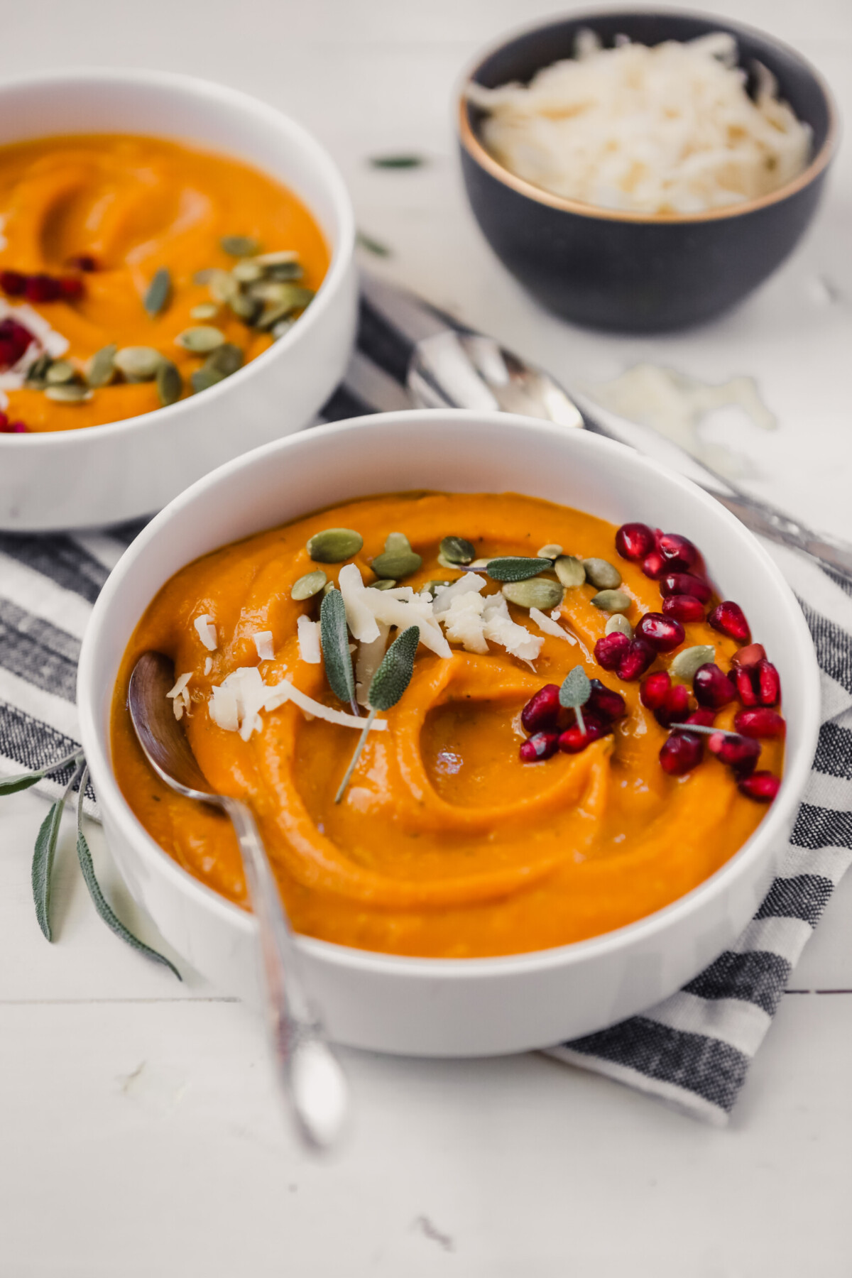 Photograph of creamy butternut squash bisque topped with pepitas and pomegranate seeds.