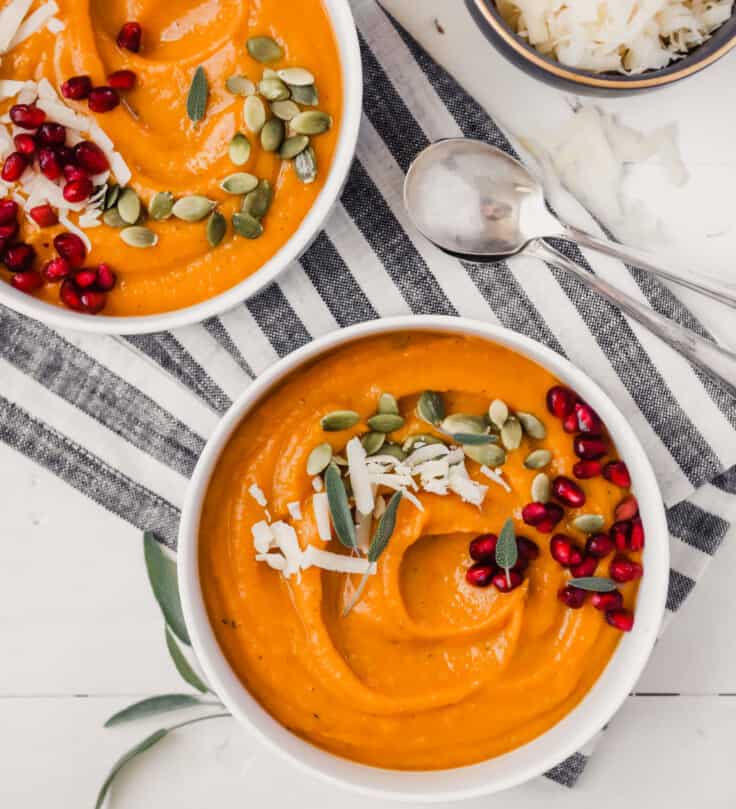 Photograph of creamy butternut squash bisque topped with pepitas and pomegranate seeds.