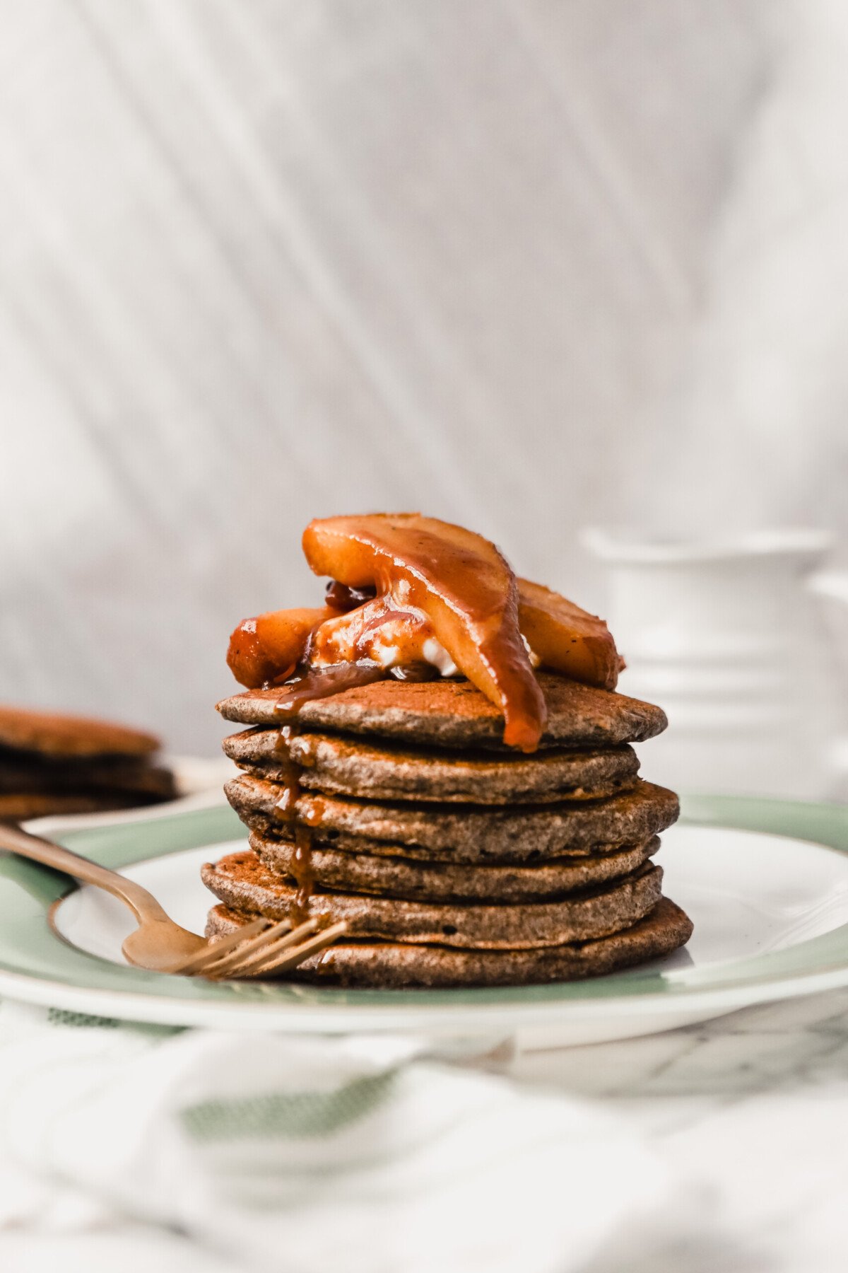 Photograph of a stack of pancakes with maple syrup dripping down them. 