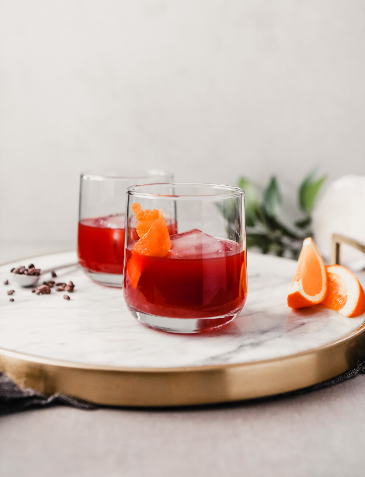 Photograph of a negroni cocktail in a rocks glass set on a white marble tray.