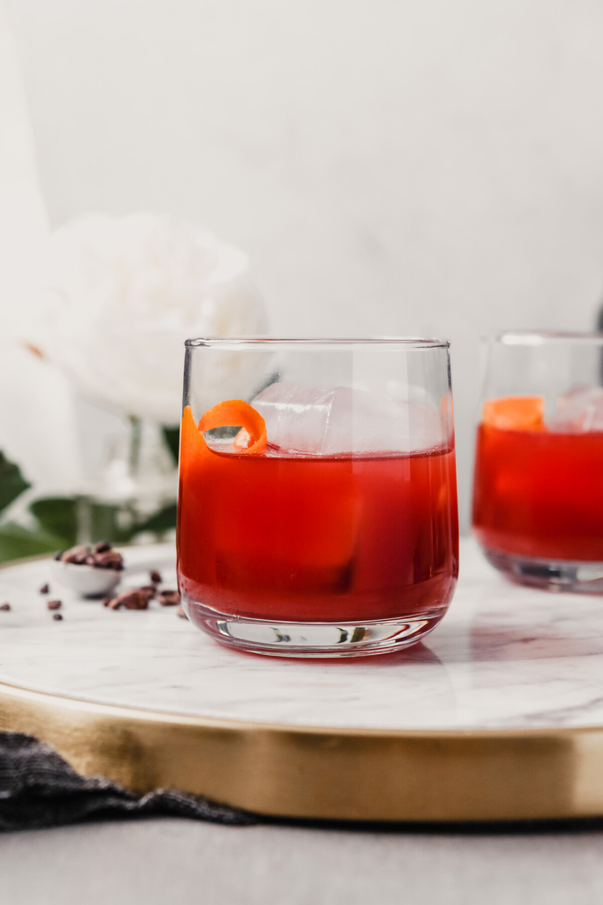 Photograph of a negroni cocktail in a rocks glass set on a white marble tray.