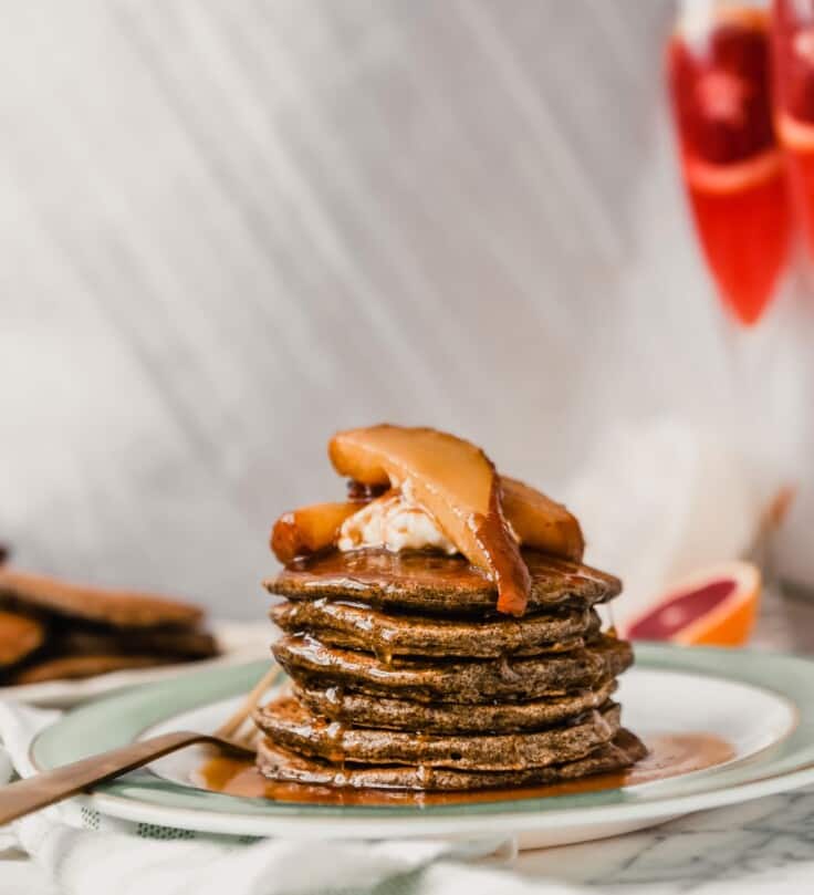 Photograph of a stack of pancakes with maple syrup dripping down them.
