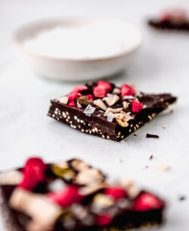 Photograph of dark chocolate coconut bark set on a white table with salt in the background