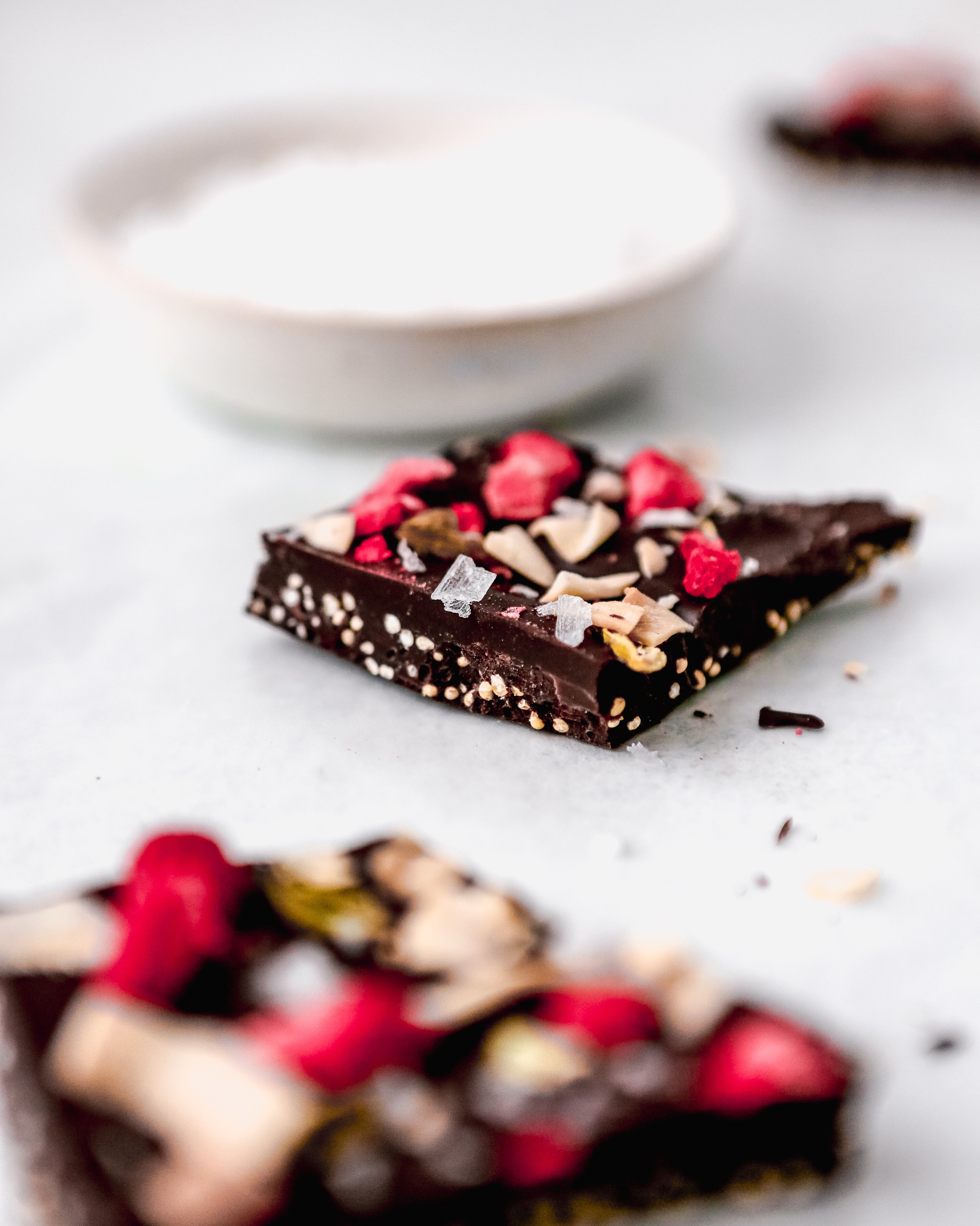 Photograph of dark chocolate coconut bark set on a white table with salt in the background
