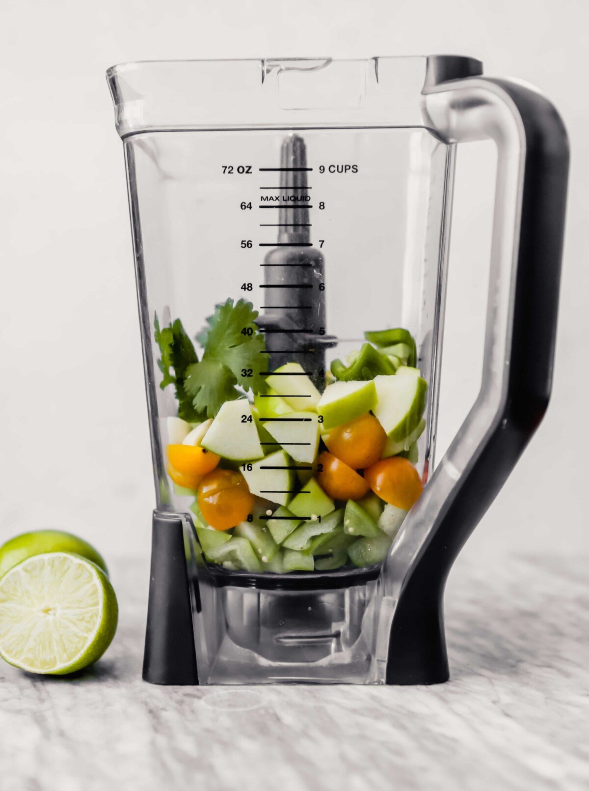 Tomatillos, cherry tomatoes, apple, and herbs in a blender