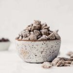 Photograph of healthy puppy chow piled into a spotted pottery bowl on a white table.