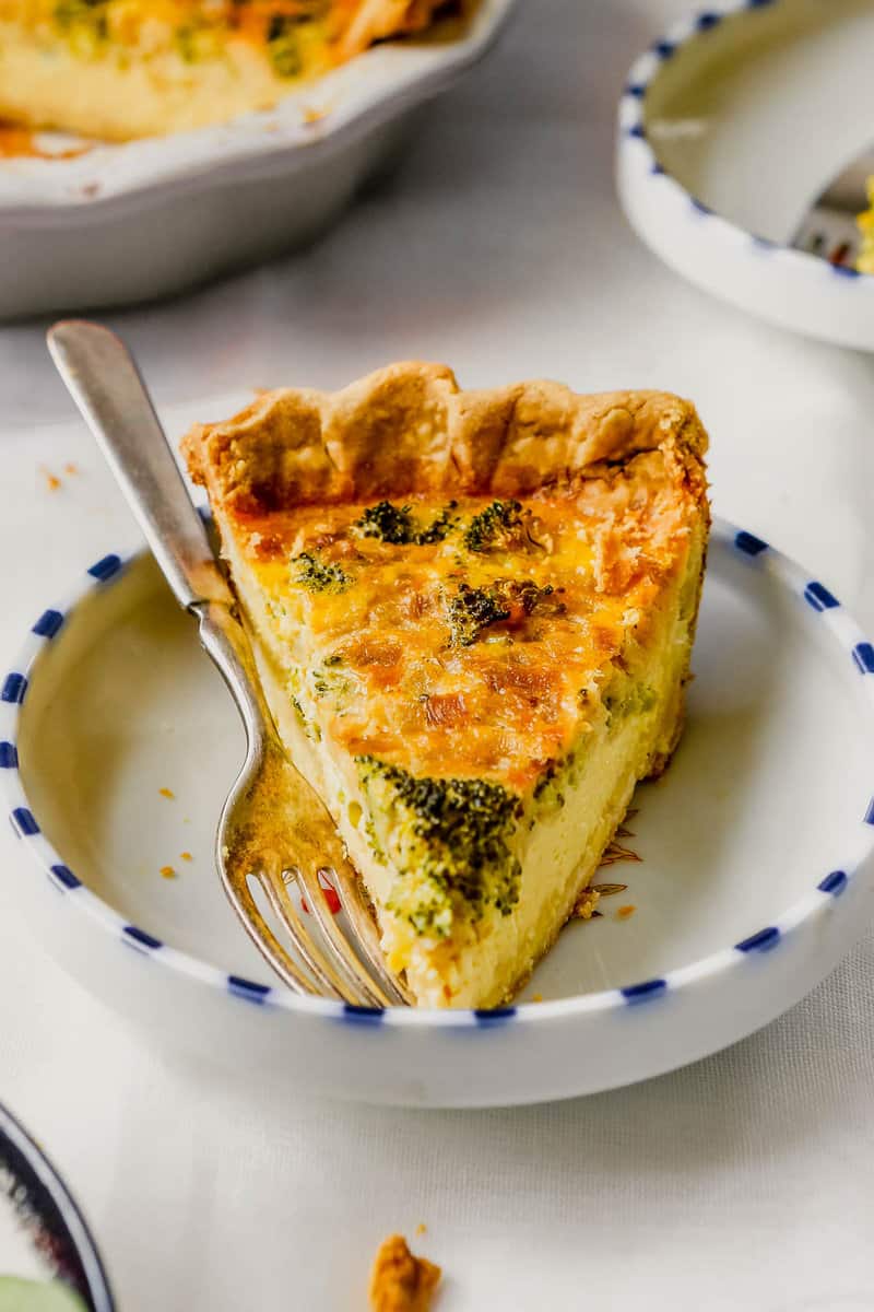 piece of broccoli quiche in a shallow white plate with blue edging