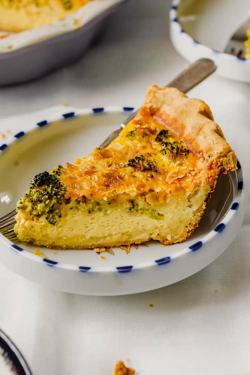 piece of broccoli quiche in a shallow white plate with blue edging