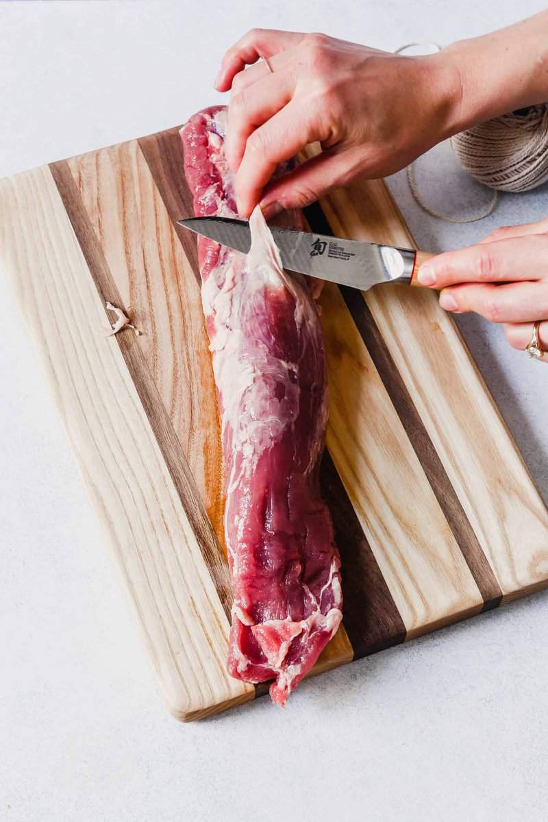 Photograph of someone trimming the silver skin from a pork tenderloin