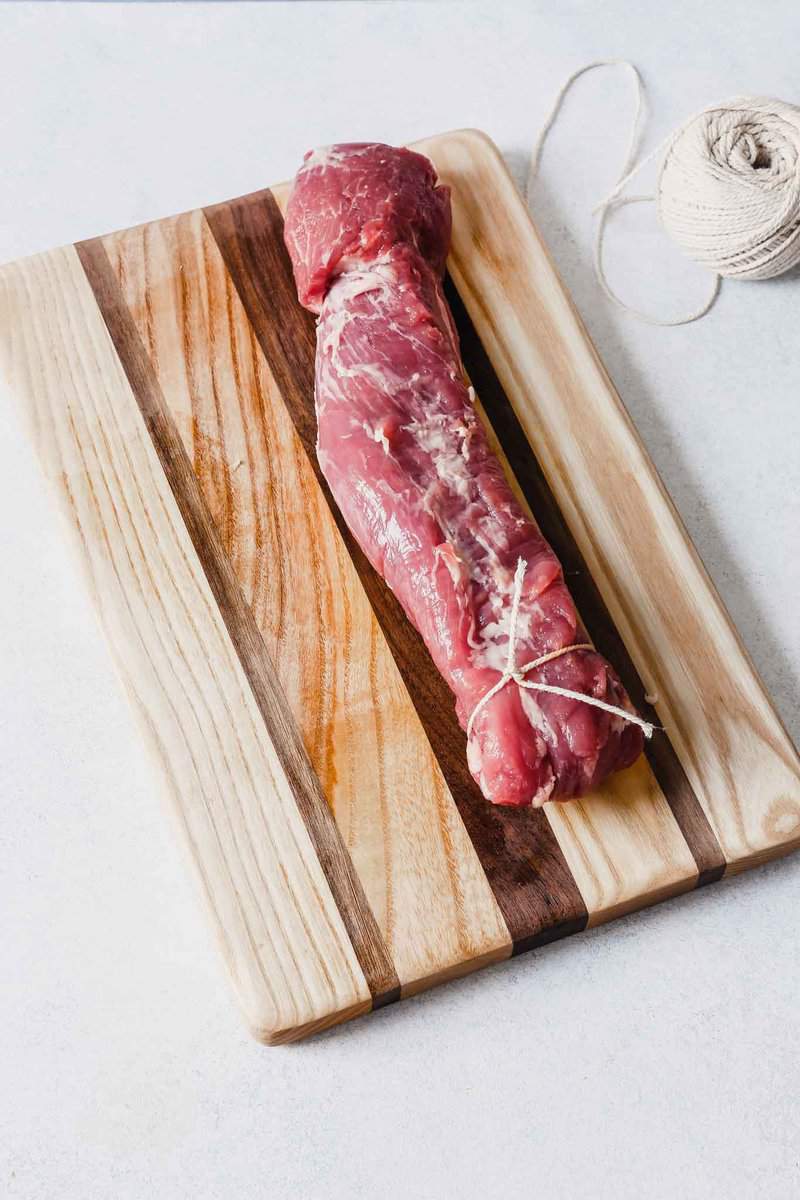 Photograph of a pork tenderloin tied with kitchen twine