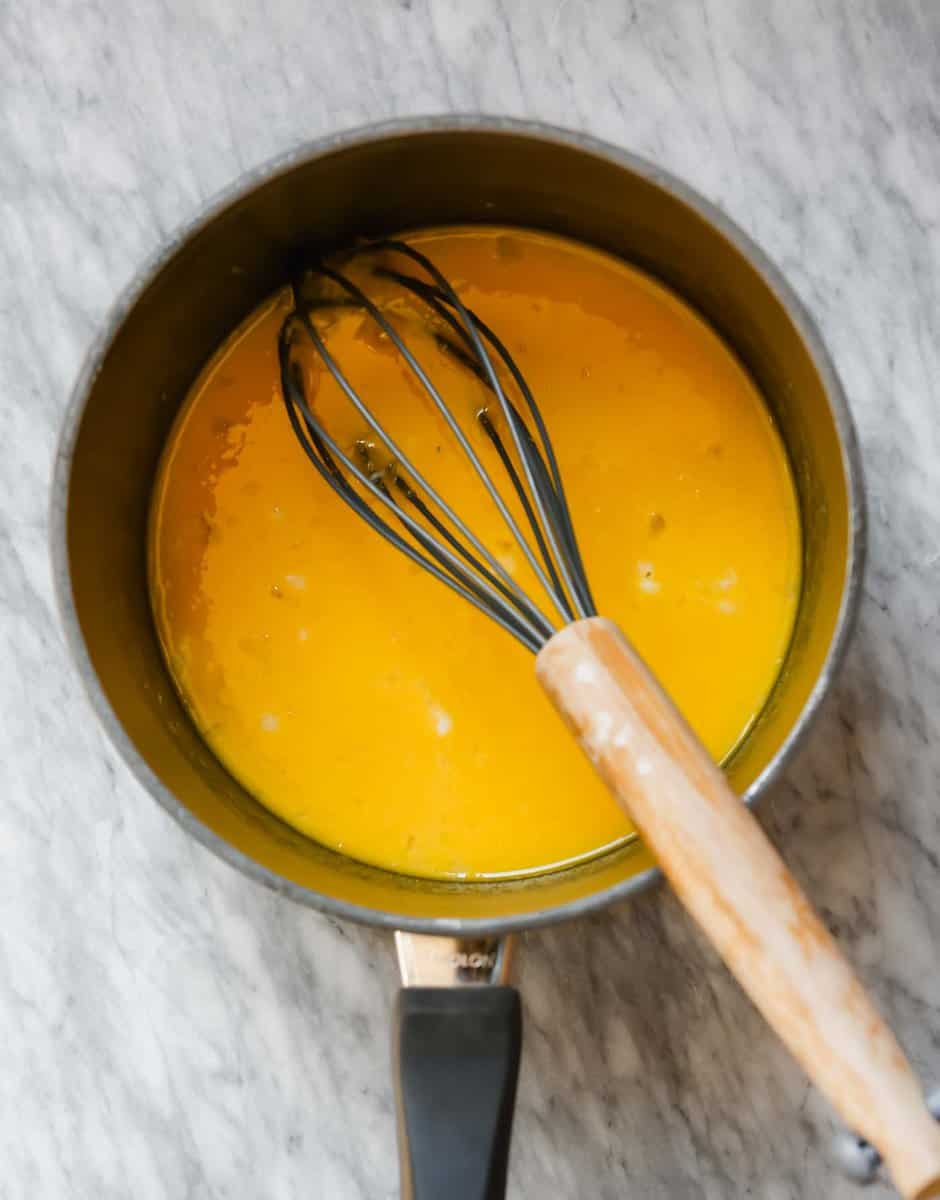 Photograph of a saucepan with with eggs, lemon juice and lemon zest whisked together in