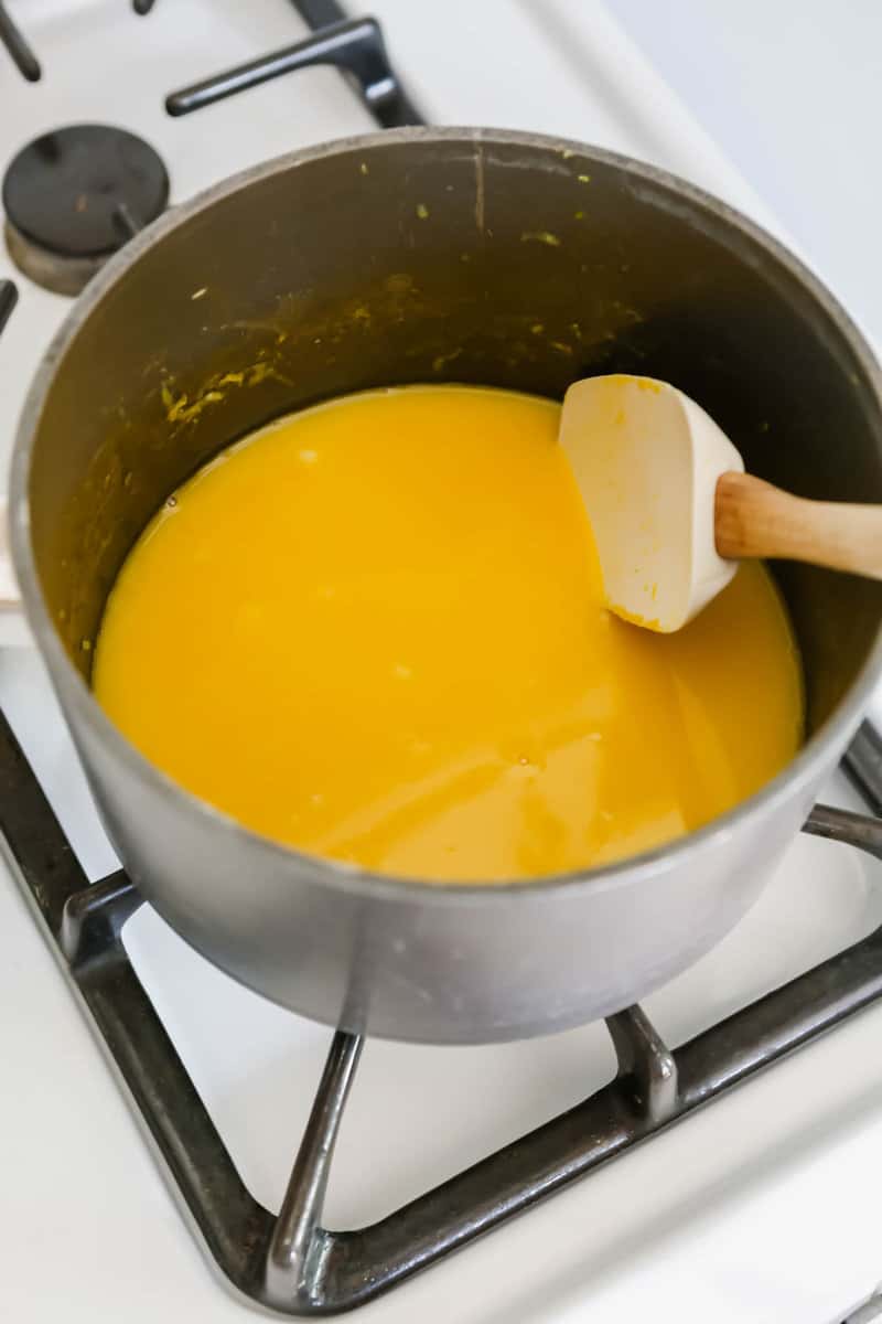 Photograph of lemon curd being cooked on the stove top with a white spatula