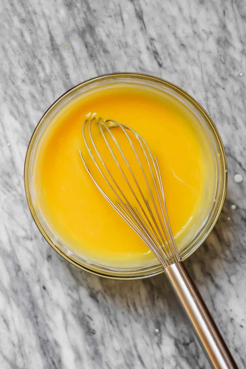 Photograph of lemon curd and whisk in a clear glass bowl