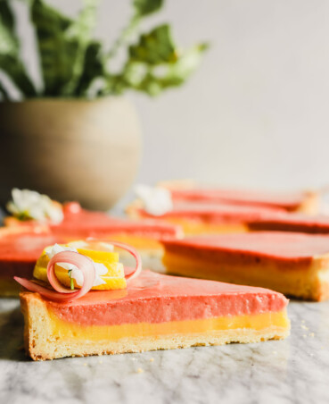 side angle photograph of wedges of layered rhubarb tart set on a marble table.