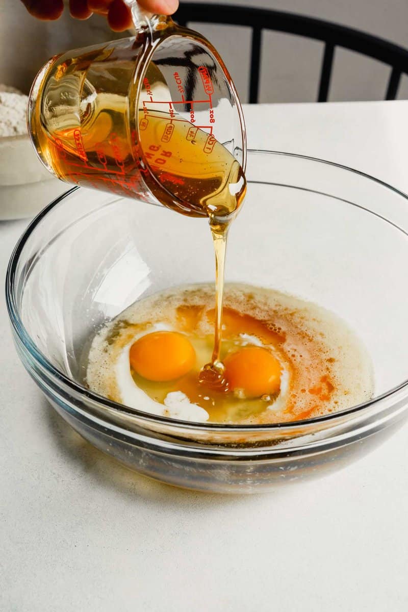 Photograph of honey being poured into a bowl with brown butter, buttermilk and eggs