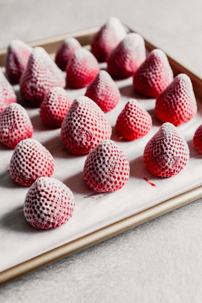 Photograph of frozen whole strawberries arranged on a baking sheet