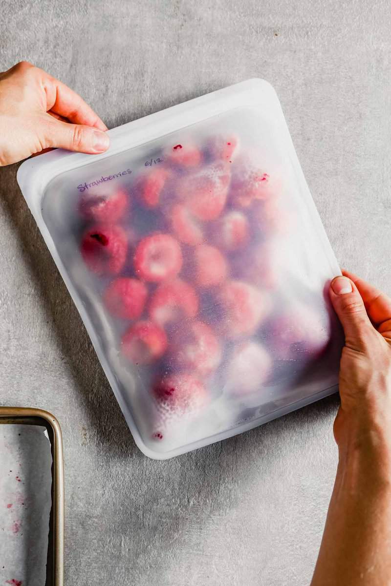 Overhead photograph of a reusable resealable bag filled with frozen whole strawberries