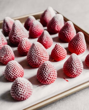 Photograph of frozen whole strawberries arranged on a baking sheet