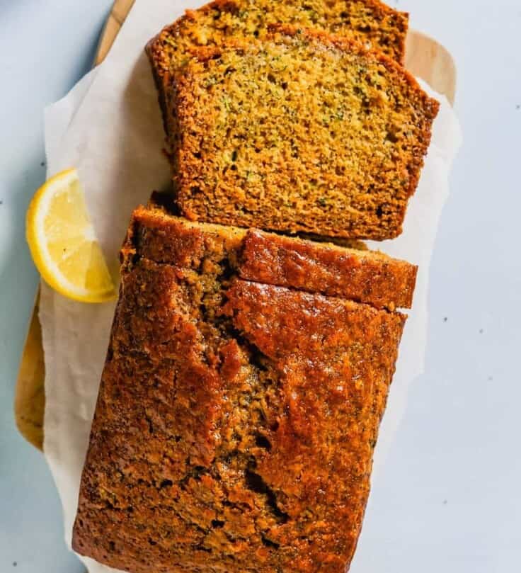 Overhead photo of lemon zucchini bread on a cutting board with a slice on a white plate