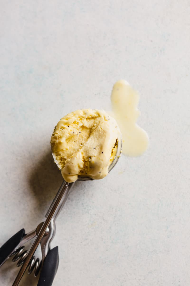 Photograph of a scoop of lemon ice cream in a an ice cream scoop set in a blue table