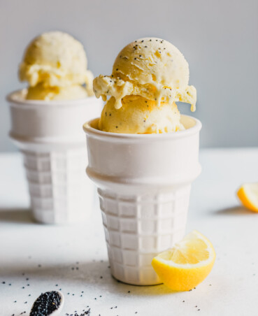Photograph of lemon ice cream scoops stacked in two white porcelain cones