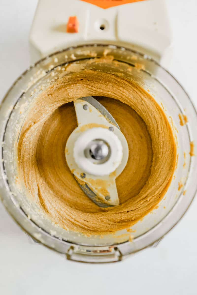 Overhead photograph of smooth cashew butter in the bowl of a food processor 