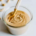 Photo of creamy cashew butter in a glass bowl with a gold spoon in it