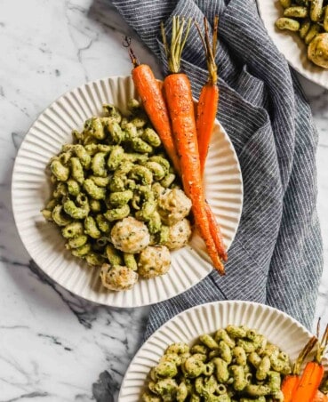 Photograph of three plates filled with carrot top pesto pasta, roasted carrots and chicken meatballs