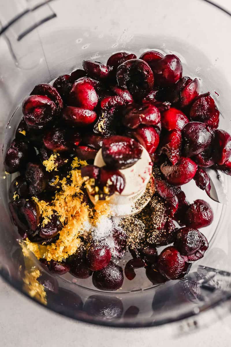 photo of cherries in a food processor with lemon zest, salt and pepper